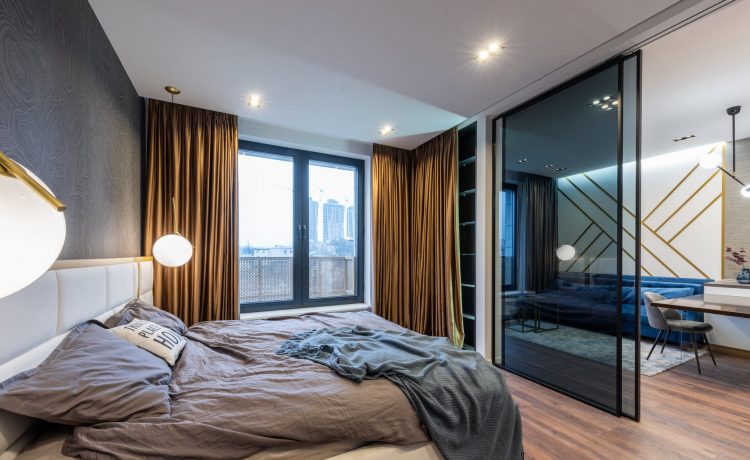 bedroom interior with unmade bed near glass door and window