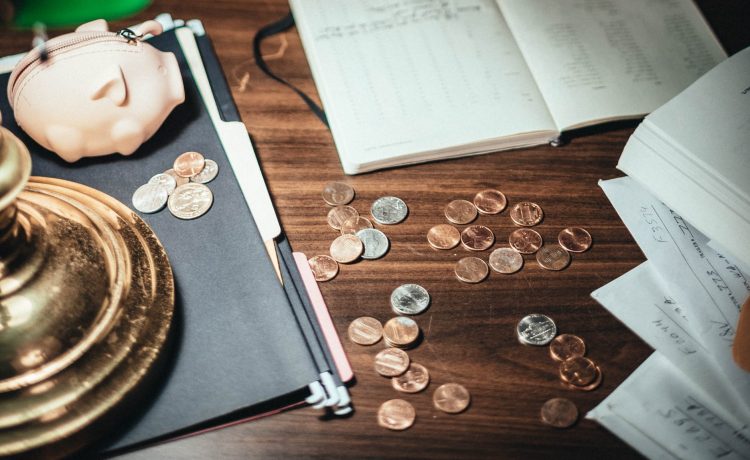 coins scattered on desk with papers and creative pig wallet